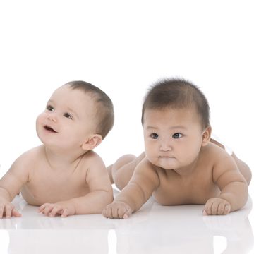 three baby boys 611 months lying down on white background