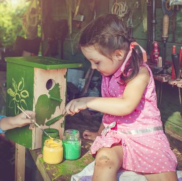 little boy and girl building and painting birdhouse outdoors in summer