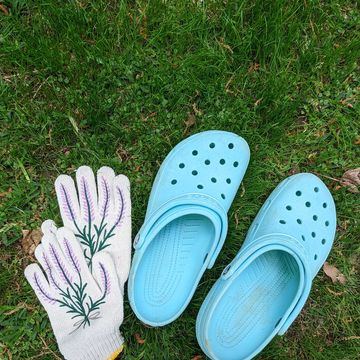 light blue crocs with garden gloves laying in grass