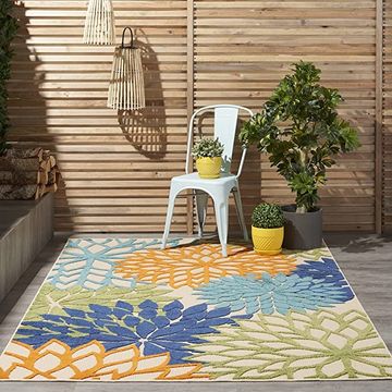 nourison aloha rug, one of the best polypropylene outdoor rugs, on a patio with vintage metal chair, potted plants