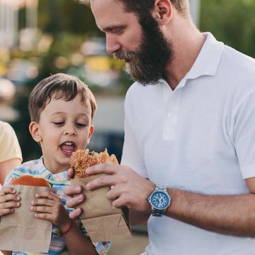 father and children eating burgers outside