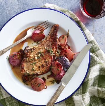 pork chops with roasted maple bacon radishes on a blue rimmed plate with a fork and knife