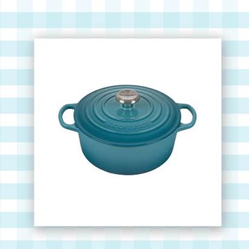 teal dutch oven and a beige votivo candle in a glass jar on a blue and white background