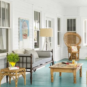 enclosed white porch with painted turquoise floor, furnished with vintage finds, at a beach cottage belonging to may kay andrews in tybee island, ga