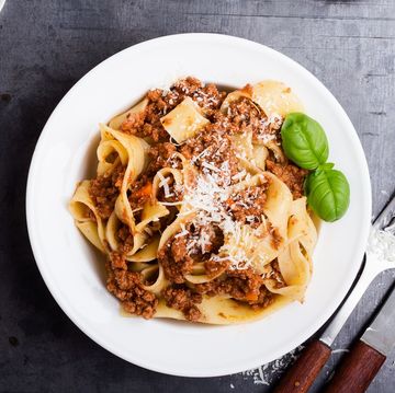 pappardelle, a ribbon shaped type of pasta, served with thick meat sauce, garnished with shredded parmesan and basil leaves