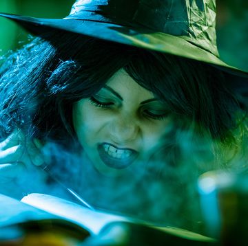 young green witch makeup with face paint reading a book