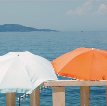 three beach umbrellas one orange one white and one blue and white in front of the ocean